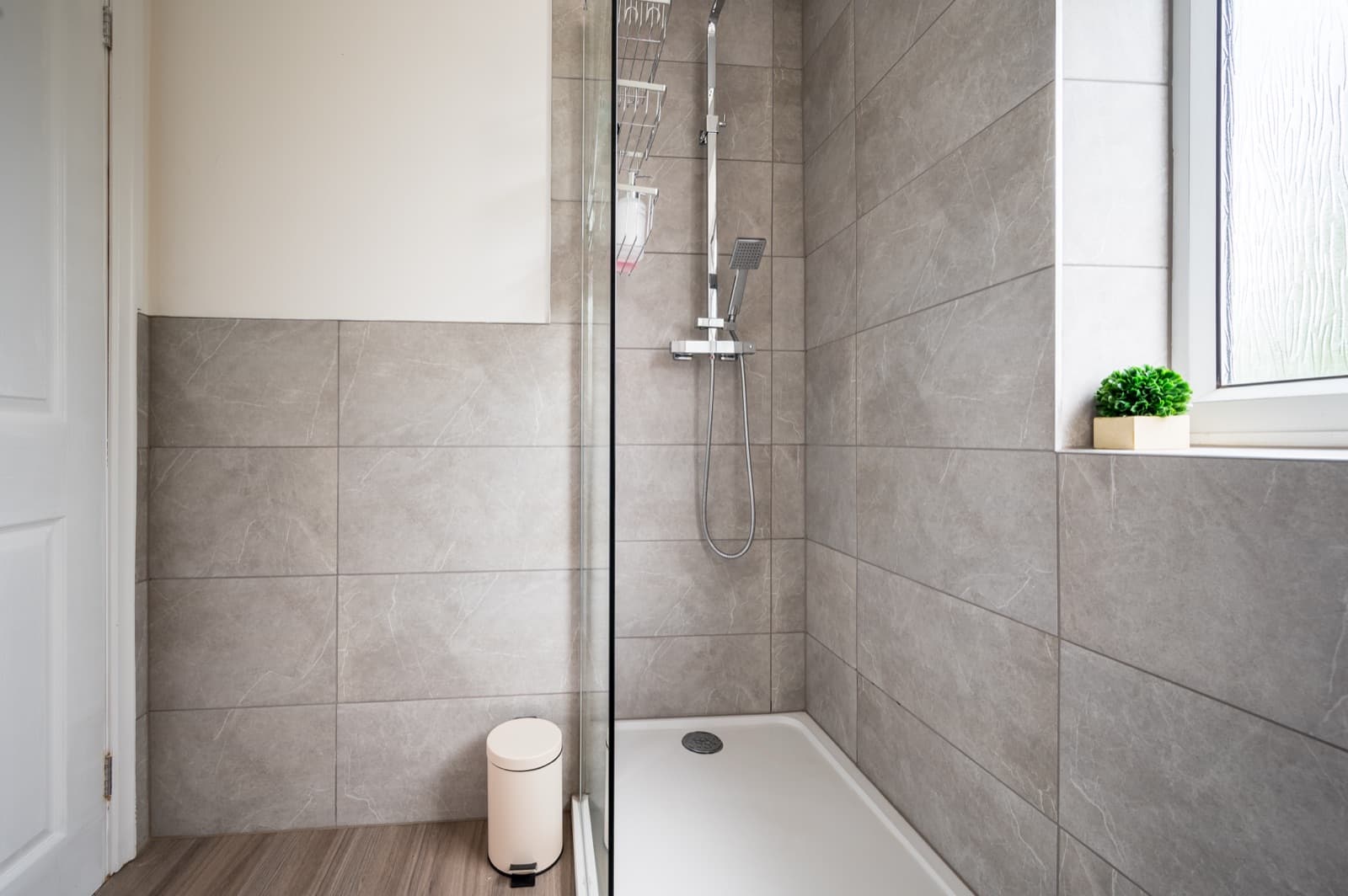 A modern walk-in shower with grey tiling